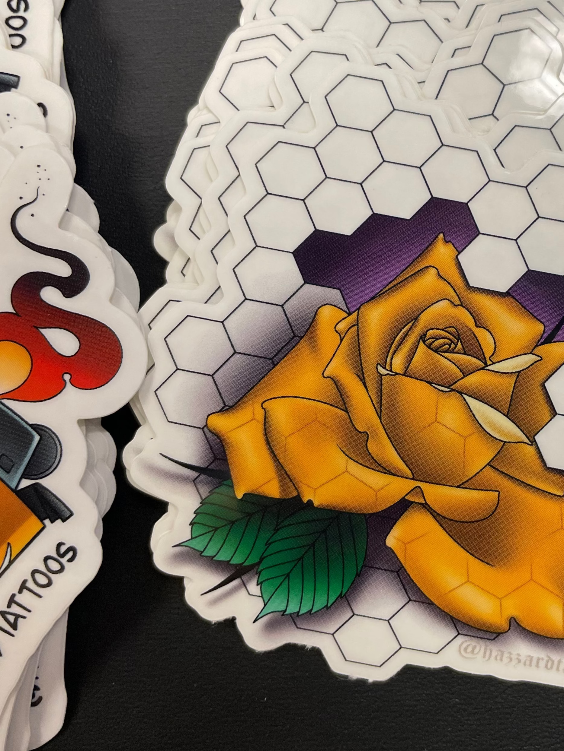 Stack of tattoo stickers with a yellow rose design on a black surface